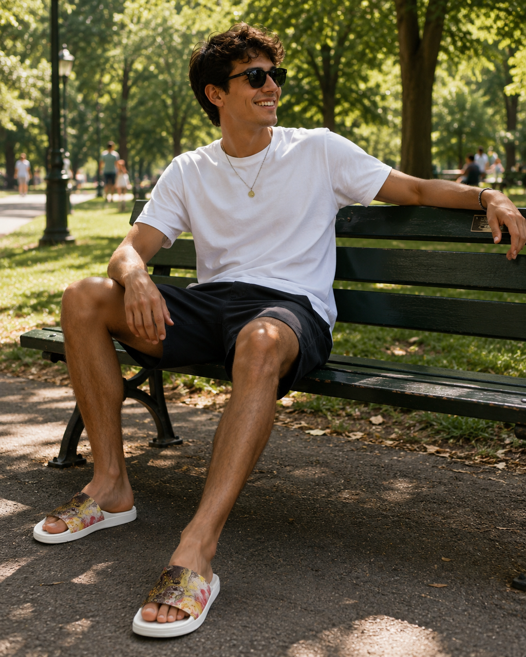 Man sitting on a park bench wearing sunglasses and casual clothing.