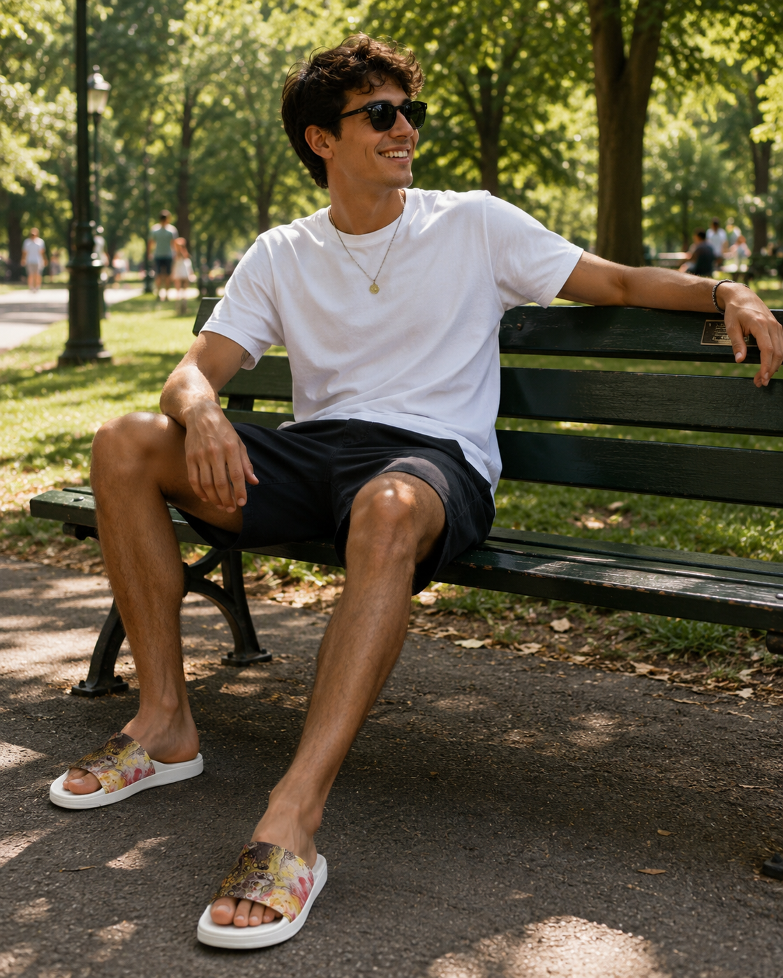 Man sitting on a park bench wearing sunglasses and casual clothing.