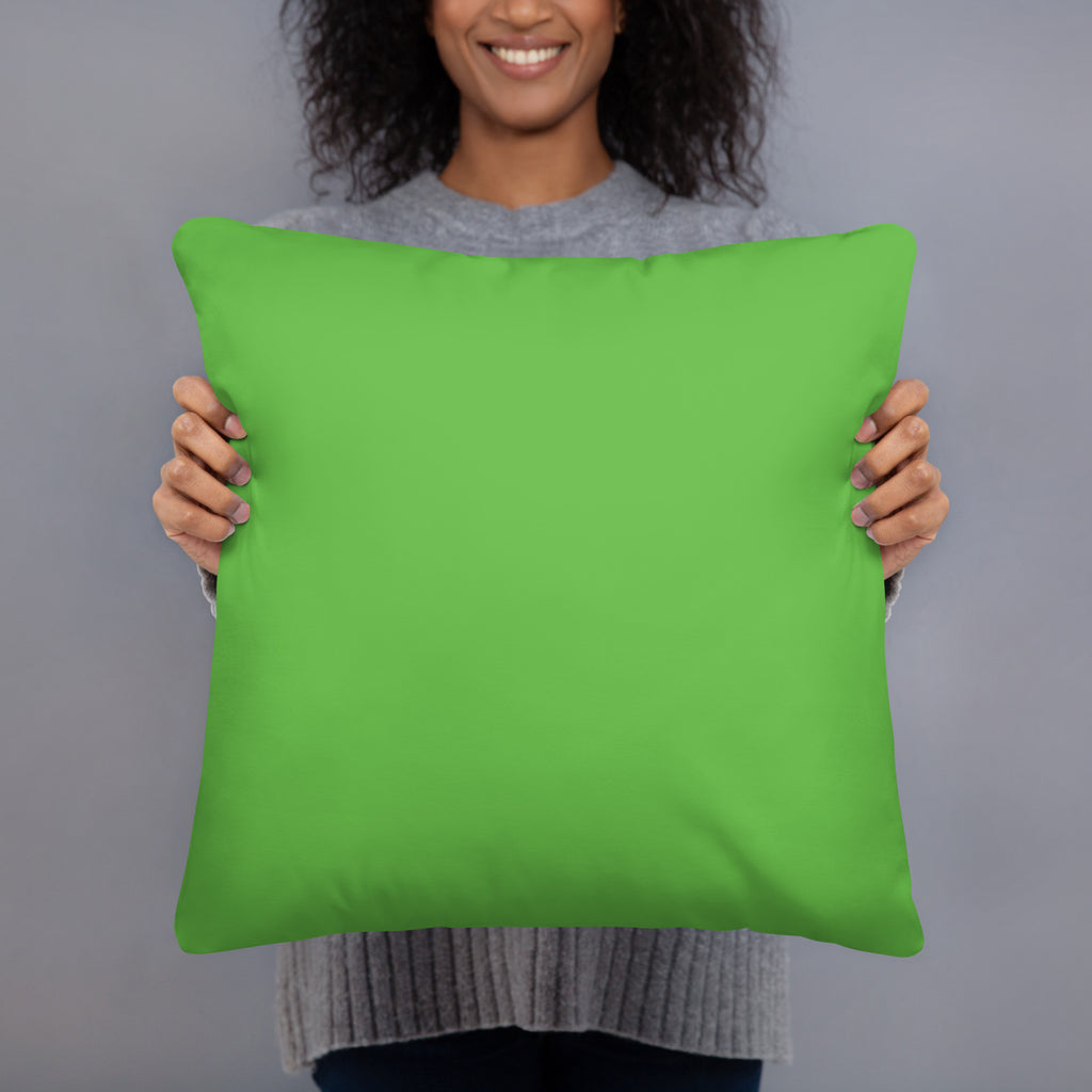 A person holding a bright lime green square throw pillow against a solid gray studio background.