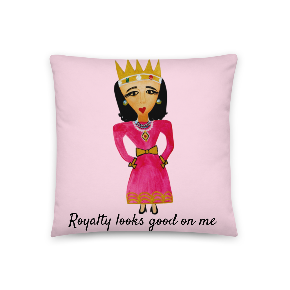 A square pink throw pillow featuring a whimsical illustration of a woman in a pink dress and gold crown with the text 'Royalty looks good on me' printed below, shown against a plain white background.