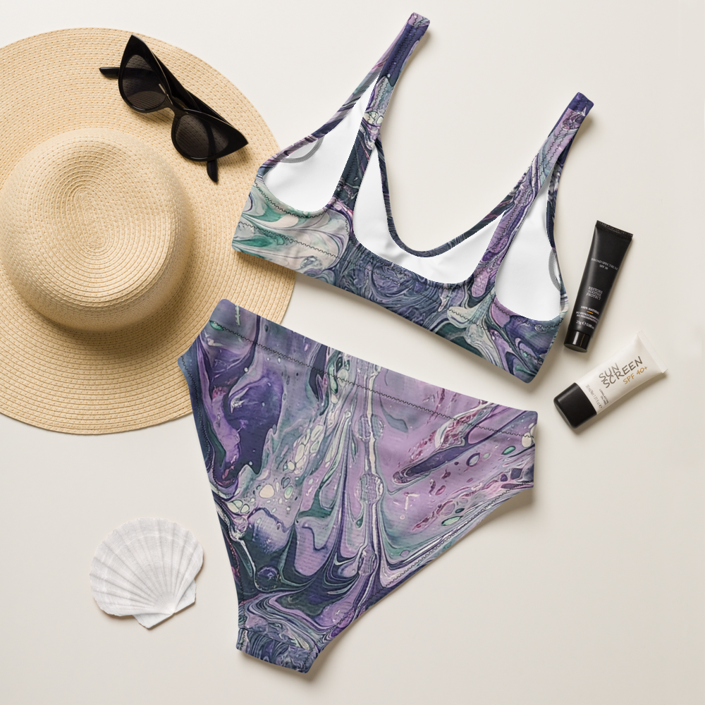 Marble-patterned bikini set with sun hat, sunglasses, and sunscreen on a light background