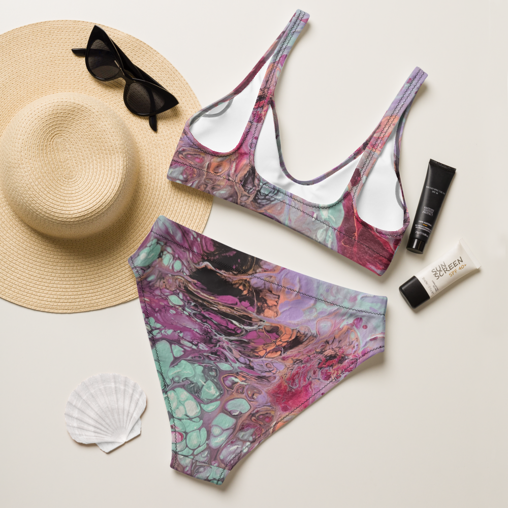 Colorful bikini set with sun hat, sunglasses, and sunscreen on a light background