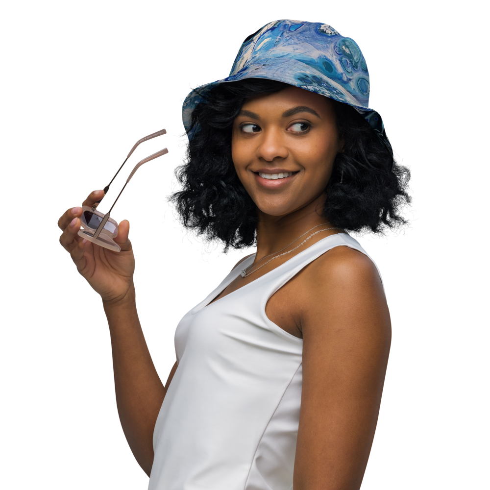 Woman wearing a blue patterned hat and white top, holding sunglasses.
