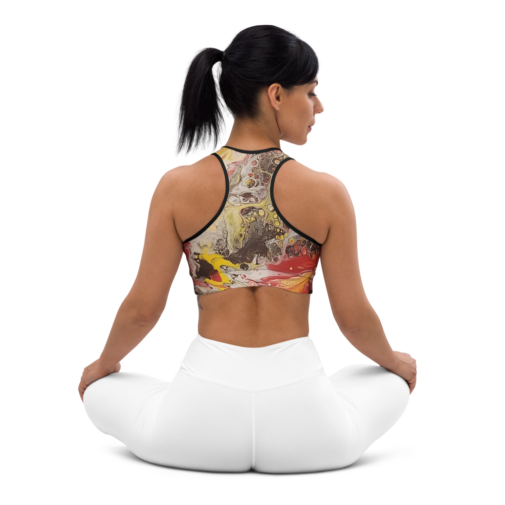 Woman sitting in a yoga pose wearing a colorful sports bra and white pants on a white background