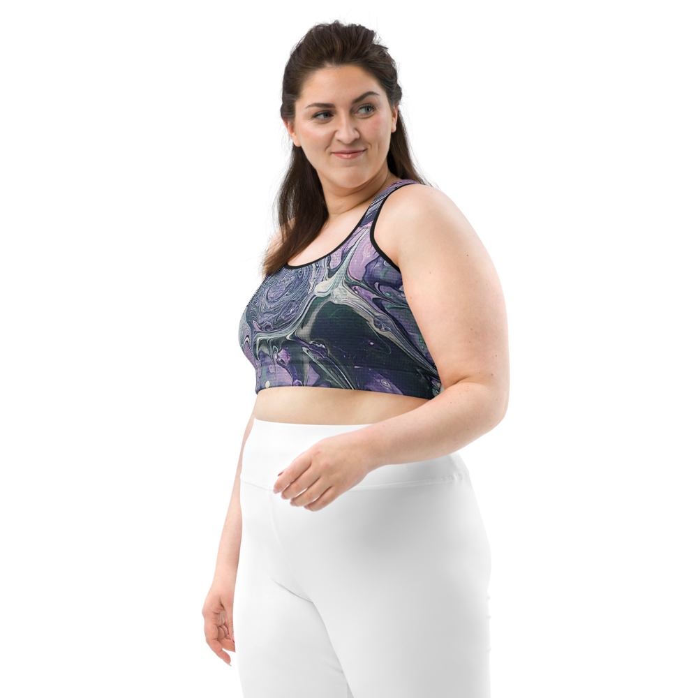 Woman wearing a patterned crop top and white pants on a white background