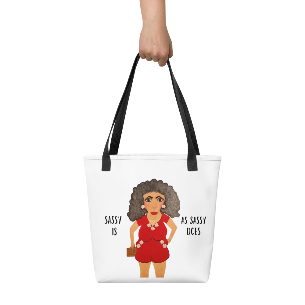 Tote bag with a graphic of a woman in a red outfit and text, held by a hand against a white background.