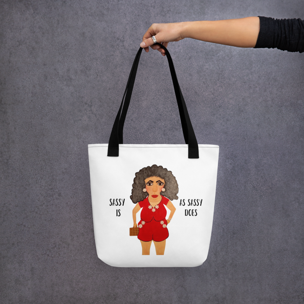 Tote bag with a graphic of a woman in a red outfit and text 'Sassy is as sassy does' on a gray background.