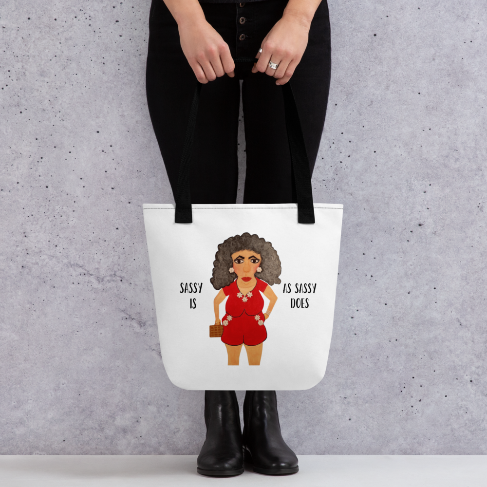 Tote bag with a cartoon character and text held by a person against a gray background