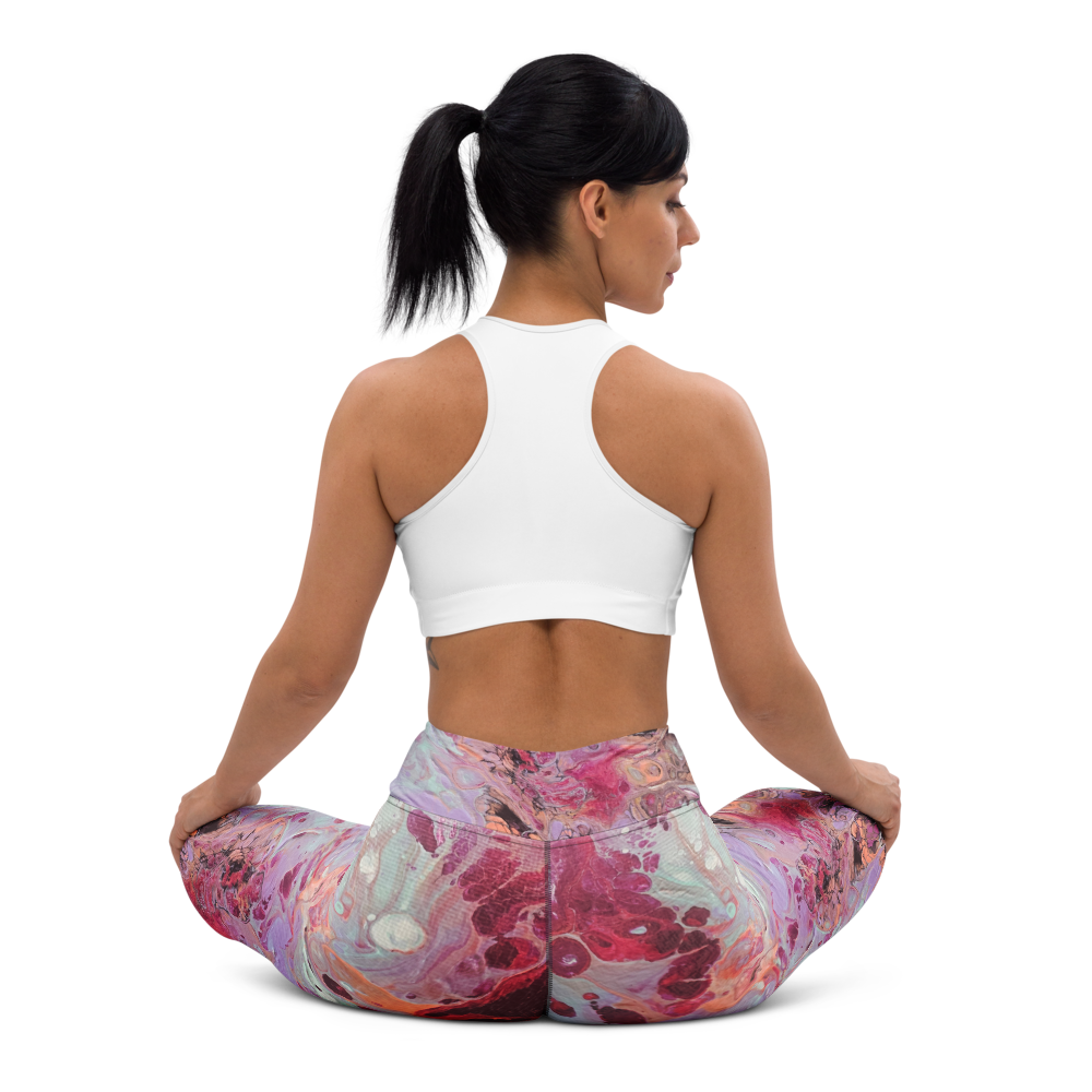 Woman sitting in a yoga pose wearing a white sports bra and colorful pants on a white background