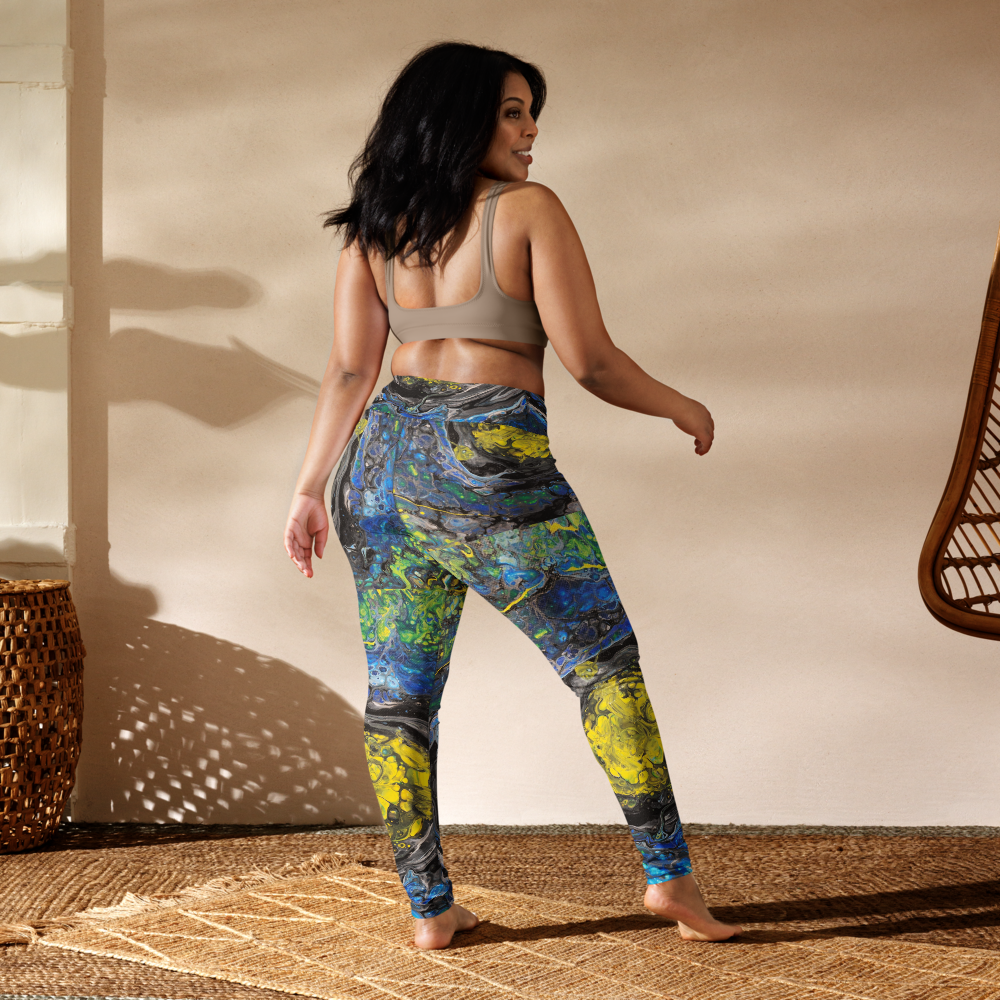 Woman wearing colorful leggings and a sports bra in a sunlit room.
