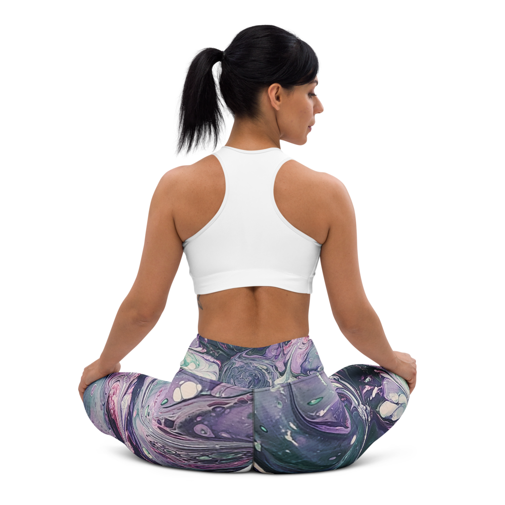 Woman sitting in a yoga pose wearing a white sports bra and colorful leggings on a white background