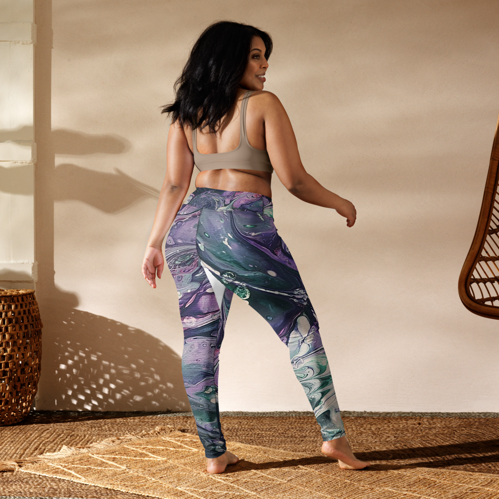 Woman wearing colorful leggings and a sports bra in a sunlit room.
