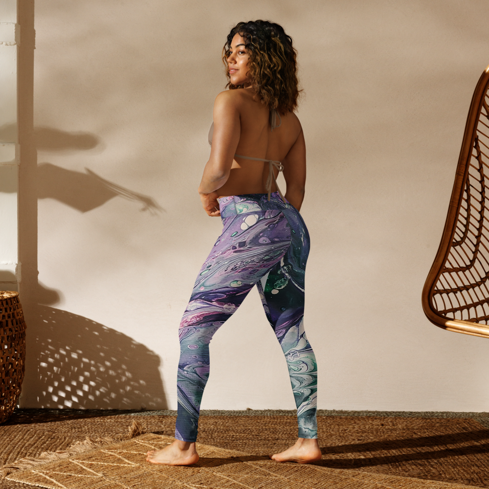 Woman wearing colorful leggings standing in a room with a wicker chair and textured wall.