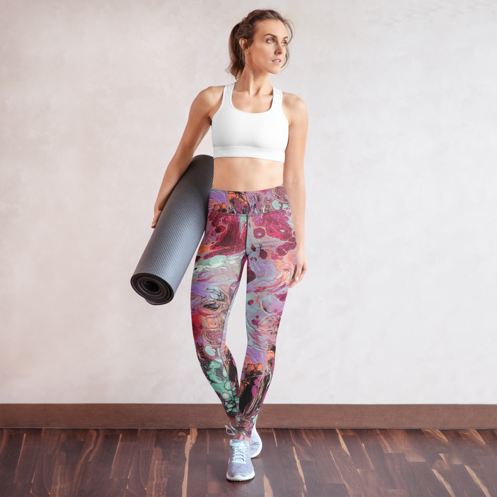 Woman holding a yoga mat wearing colorful leggings and a white sports bra.
