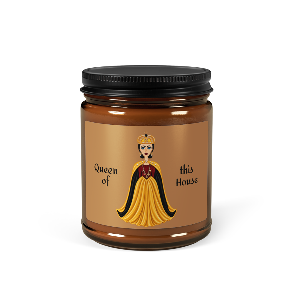 An amber glass jar candle with a black metal lid and a tan label featuring an illustration of a queen in a yellow gown and the text 'Queen of this House'.
