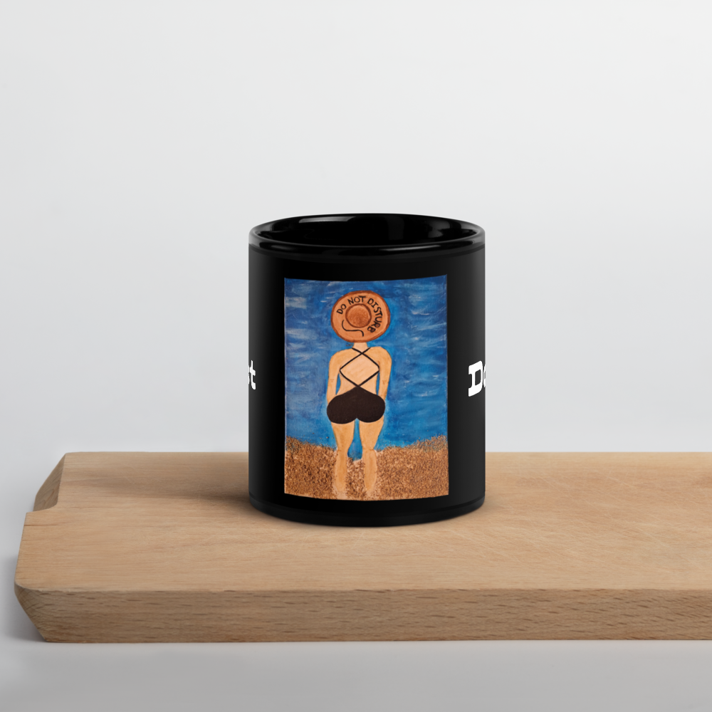 A black ceramic mug with a colorful printed illustration of a woman from behind wearing a sombrero and black swimsuit, standing on a wooden surface against a light gray background.