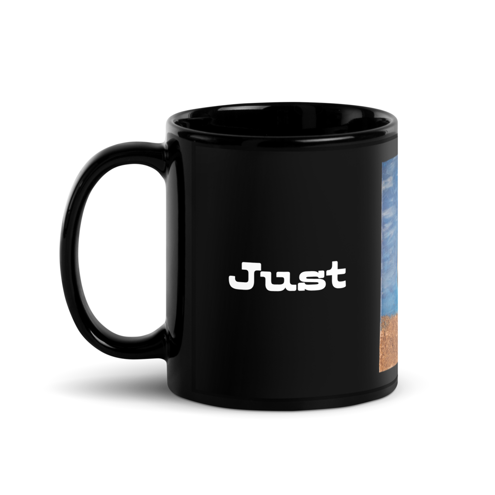 A glossy black ceramic mug with the word 'Just' printed in white lowercase letters on the front, shown against a plain white background.