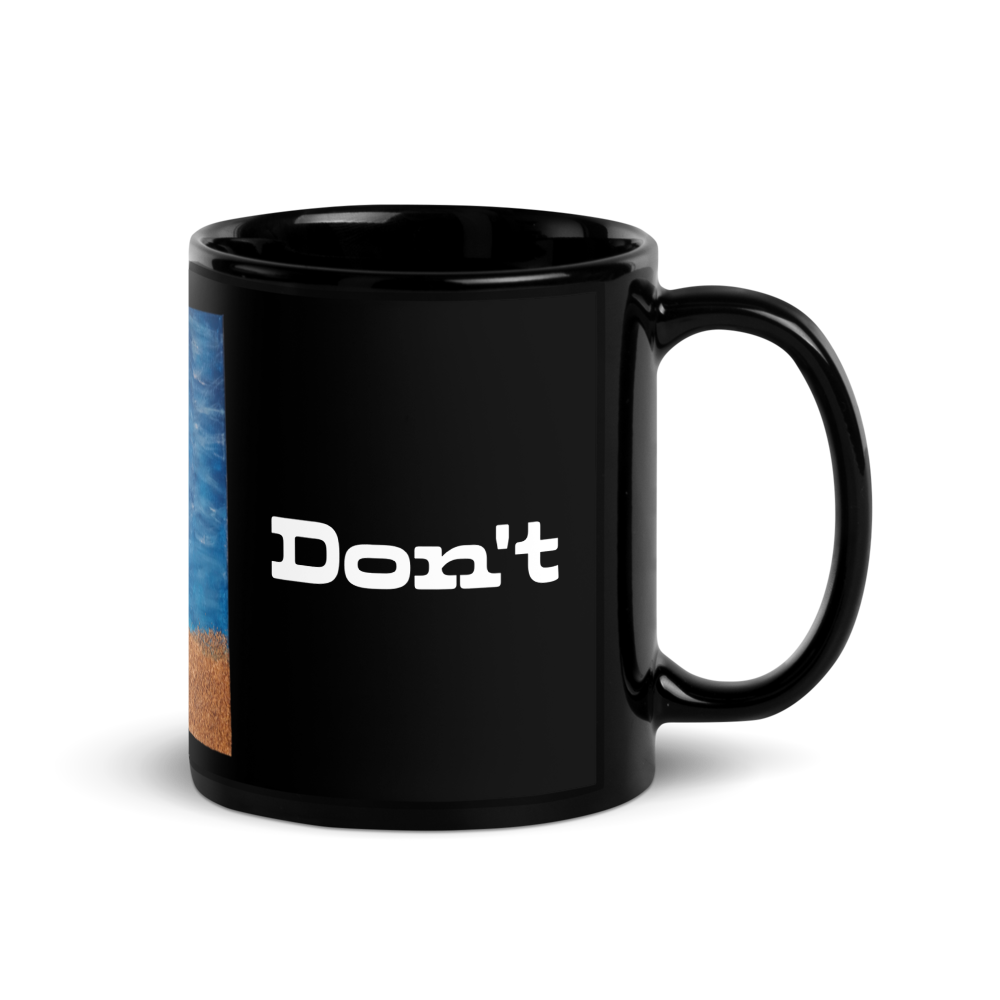 A glossy black ceramic mug with a handle, featuring the text 'Don't' printed in white on the front and a partial beach scene graphic on the left side, set against a plain white background.