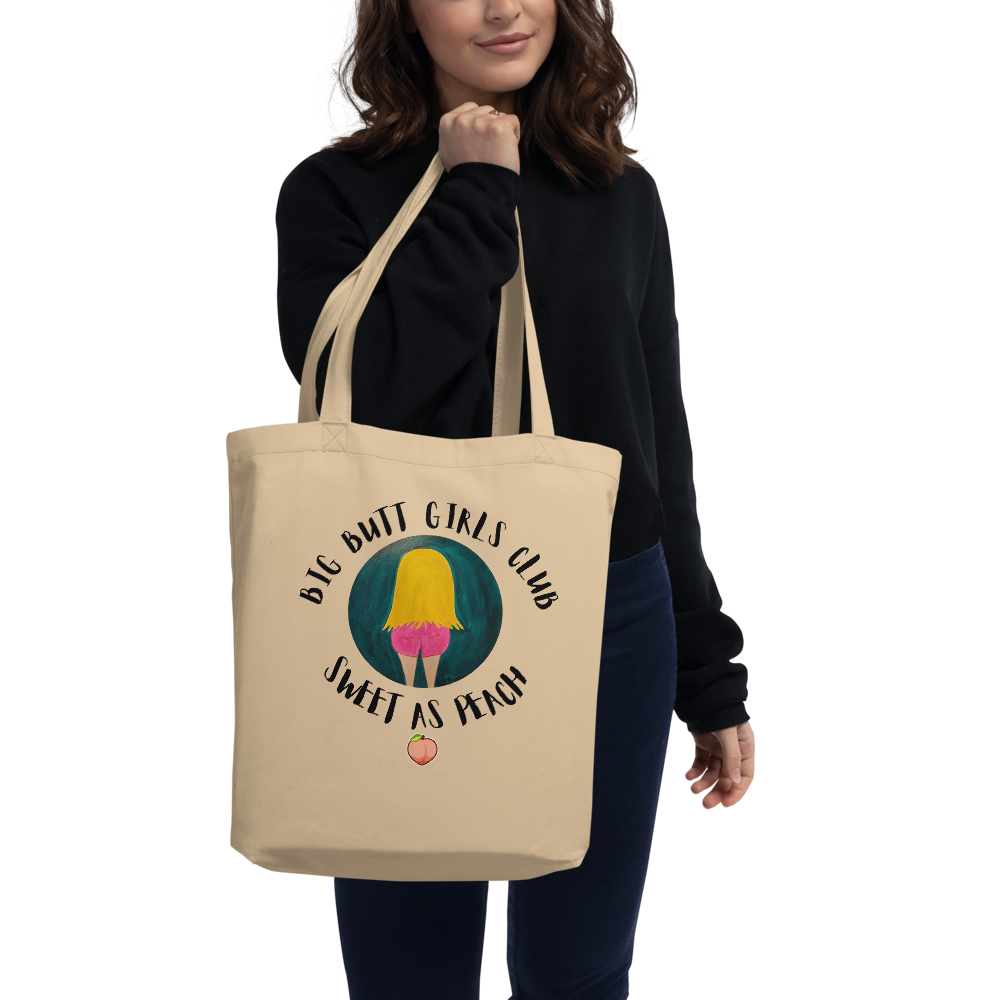Person holding a beige tote bag with a graphic design and text.