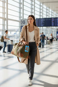 a picture of a young woman at the airport carrying a duffel bag