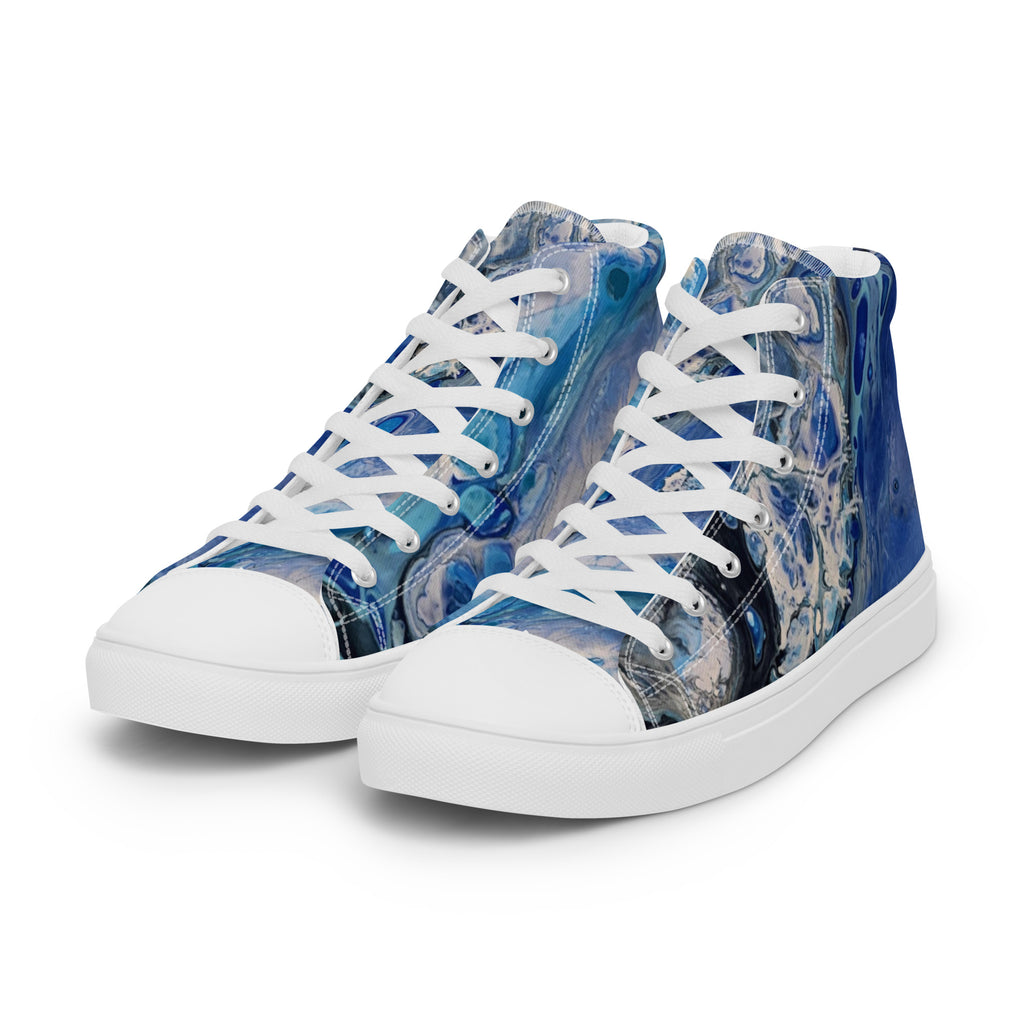 Blue patterned sneakers worn with rolled-up jeans on a white background