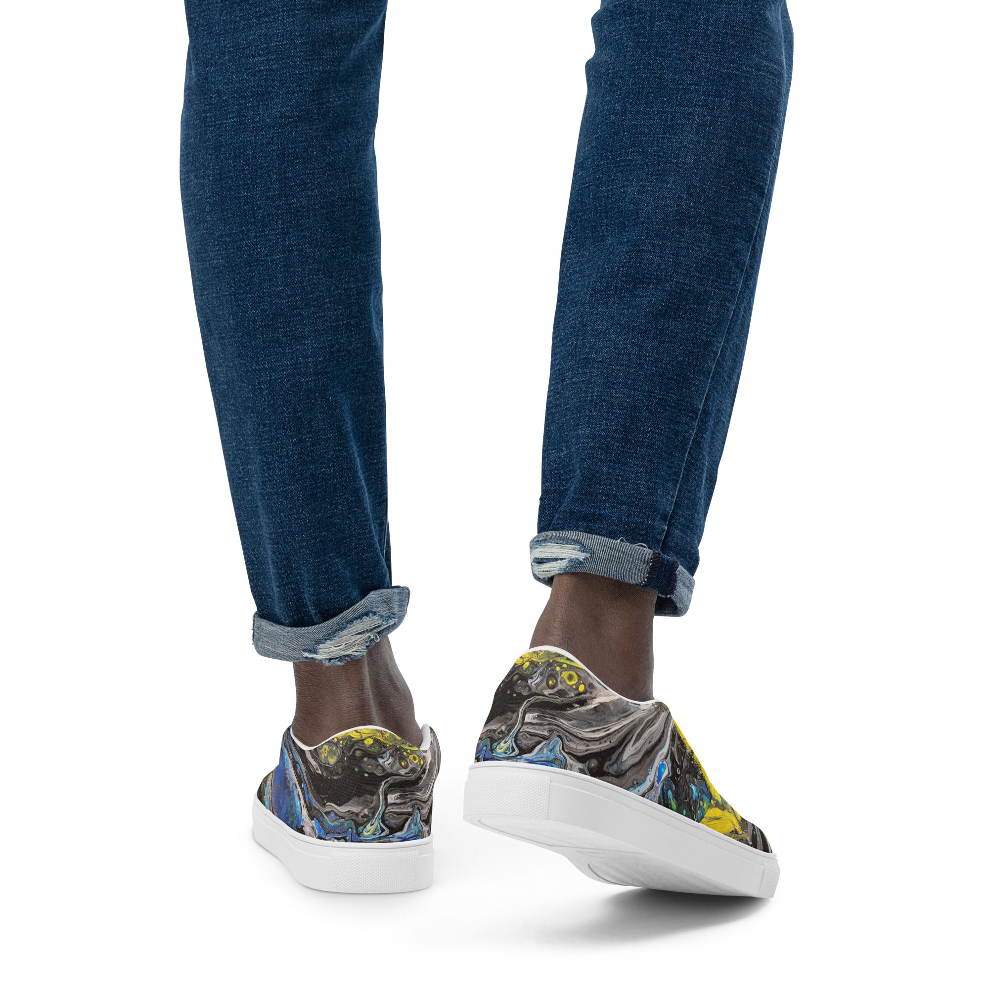 Person wearing blue jeans and patterned sneakers on a white background