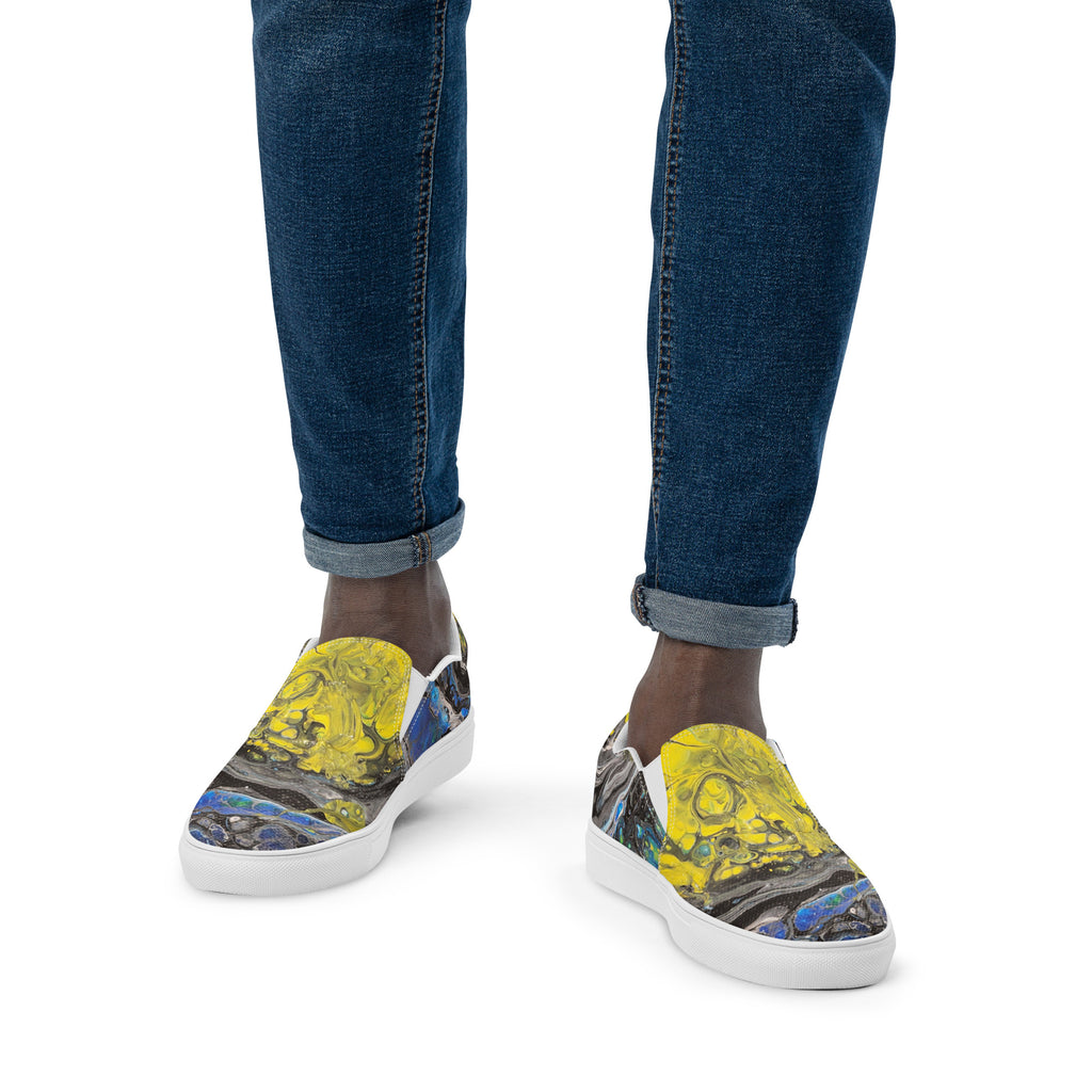 Colorful sneakers with artistic design worn with blue jeans on a white background