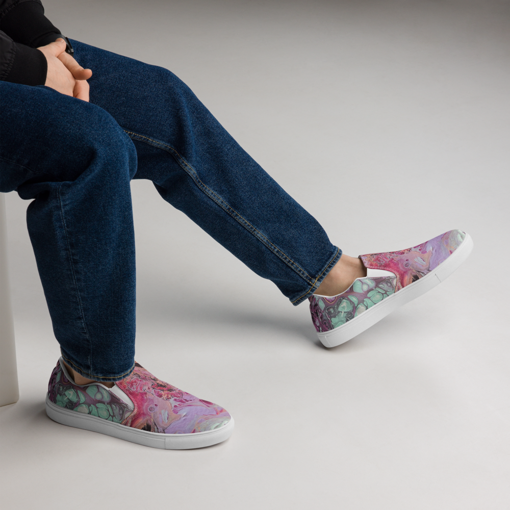 Person wearing floral slip-on shoes with blue jeans on a neutral background