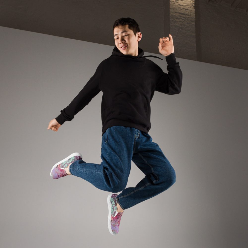 Person in black hoodie and blue jeans jumping in the air against a gray background
