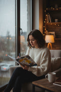 image of a young woman sitting by a window during a rainstorm while writing into a notebook