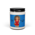 A white scented candle in a clear glass jar with a black metal lid, featuring a blue label with an illustration of a woman in a red outfit and the text 'Sassy is as Sassy Does'.