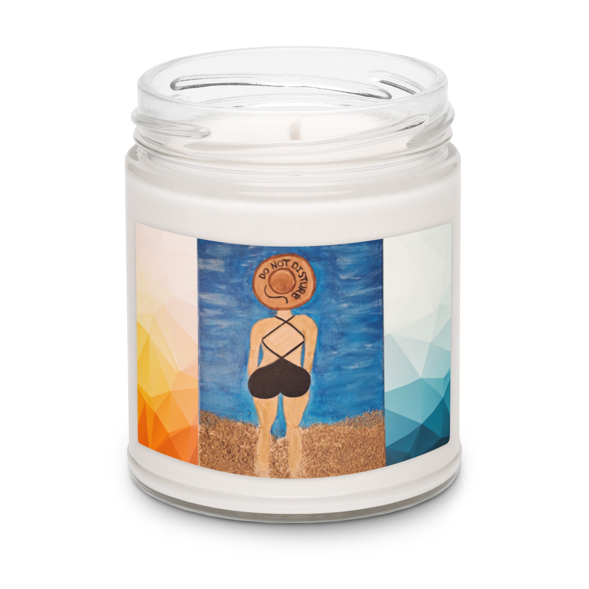 A white wax candle in a clear glass jar with a printed wrap label showing an illustration of a woman from behind on a beach, wearing a sun hat and black swimsuit against a blue sky.