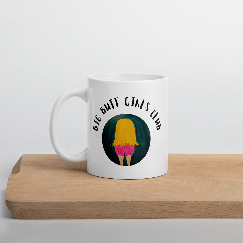 White mug with 'Big Butt Girls Club' design on a wooden surface