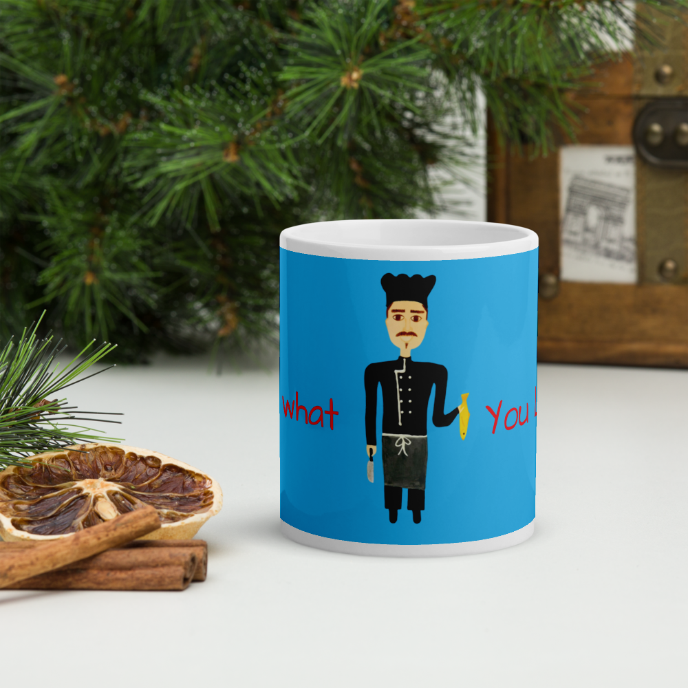 Blue mug with a character design and text, placed on a surface with Christmas decorations.