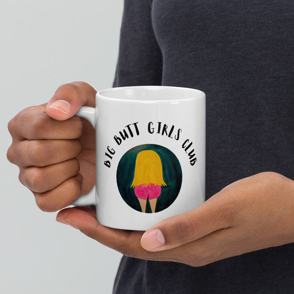 Person holding a white mug with 'Big Butt Girls Club' design on a plain background
