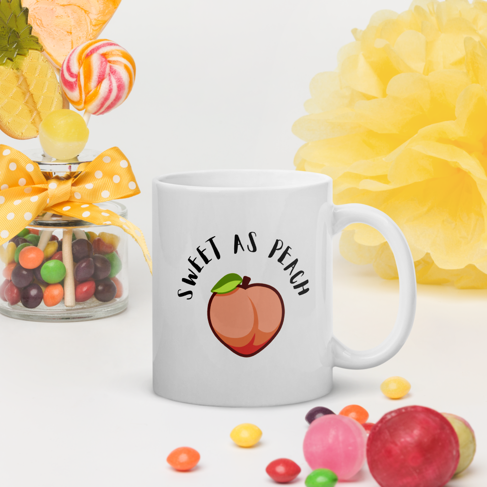 White mug with 'Sweet as Peach' design surrounded by colorful candies and flowers on a light background