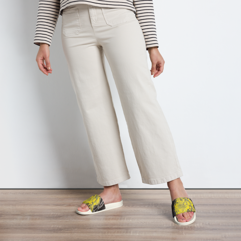 Person wearing white pants and yellow sandals on a wooden floor.