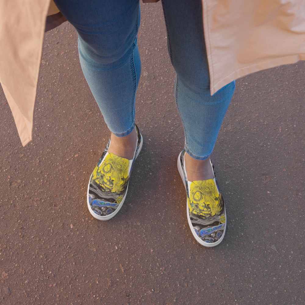 Person wearing blue jeans and colorful sneakers on a pavement.