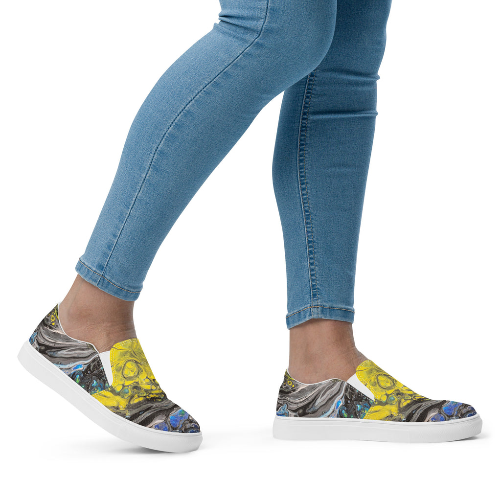 Colorful sneakers with abstract design worn with blue jeans on a white background
